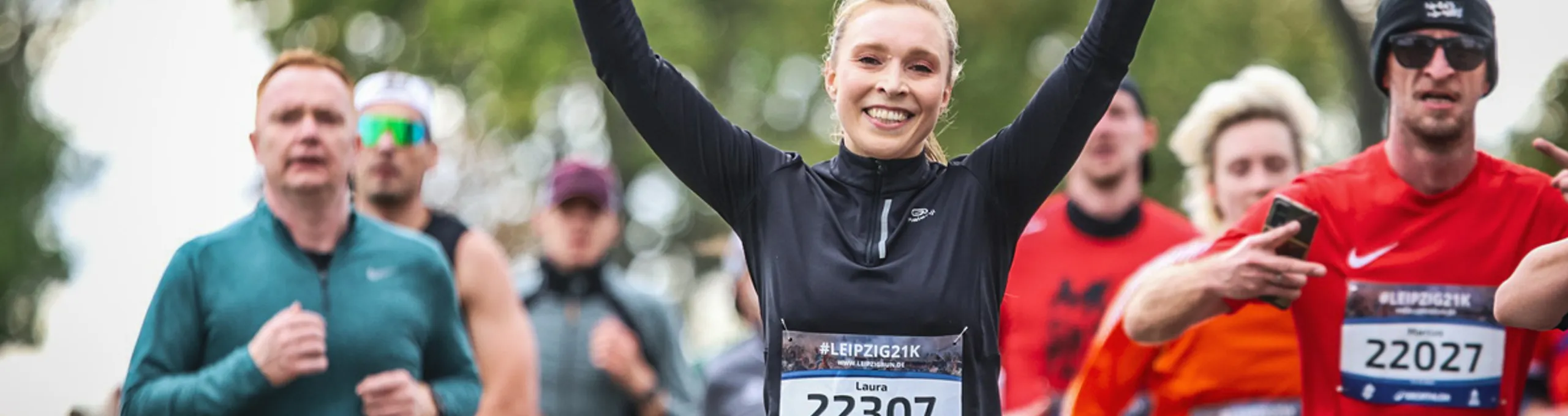 Glückliche Läuferin winkt in die Kamera