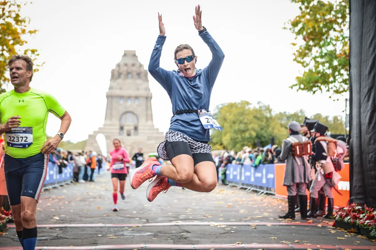 Läuferin springt über die Ziellinie des Leipzig Run