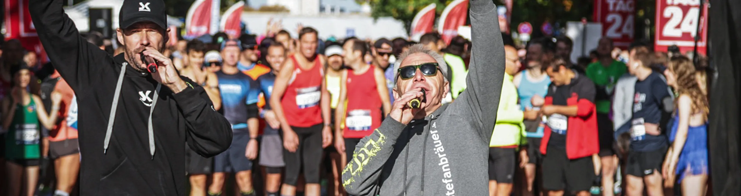 Event-Moderatoren stehen vor wartenden Läufern und machen Stimmung