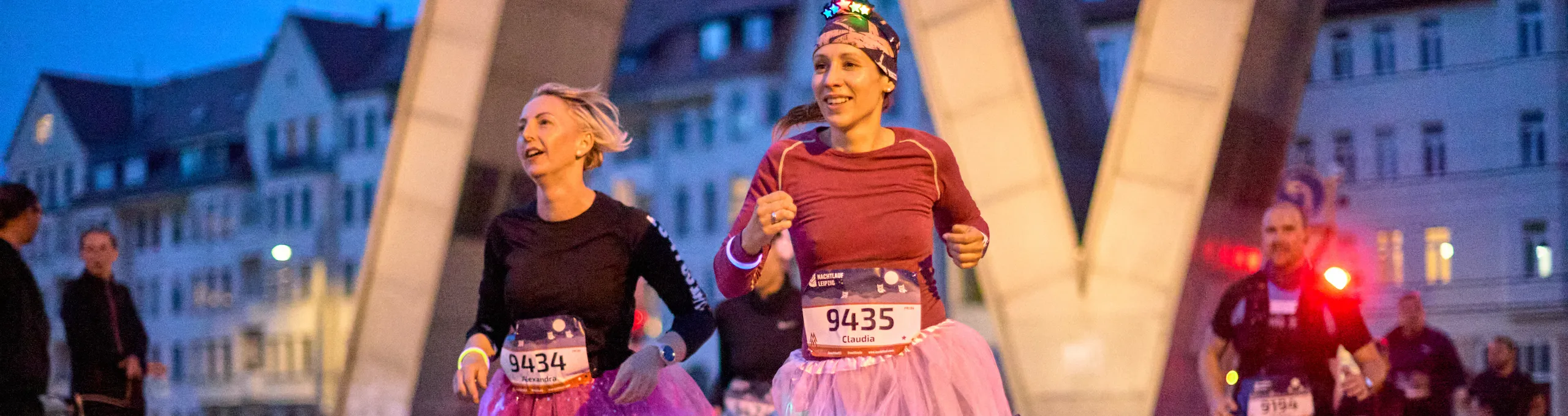 Läuferinnen laufen mit leuchtenden Kostümen durch das Doppel M