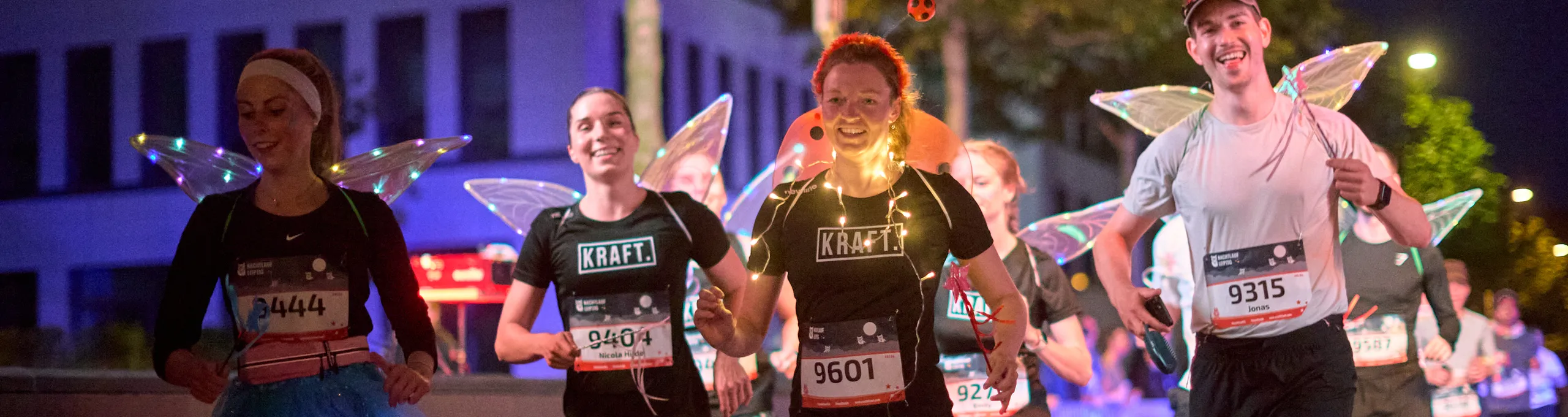Gruppe von Läufern mit Feenflügeln und Leuchtketten