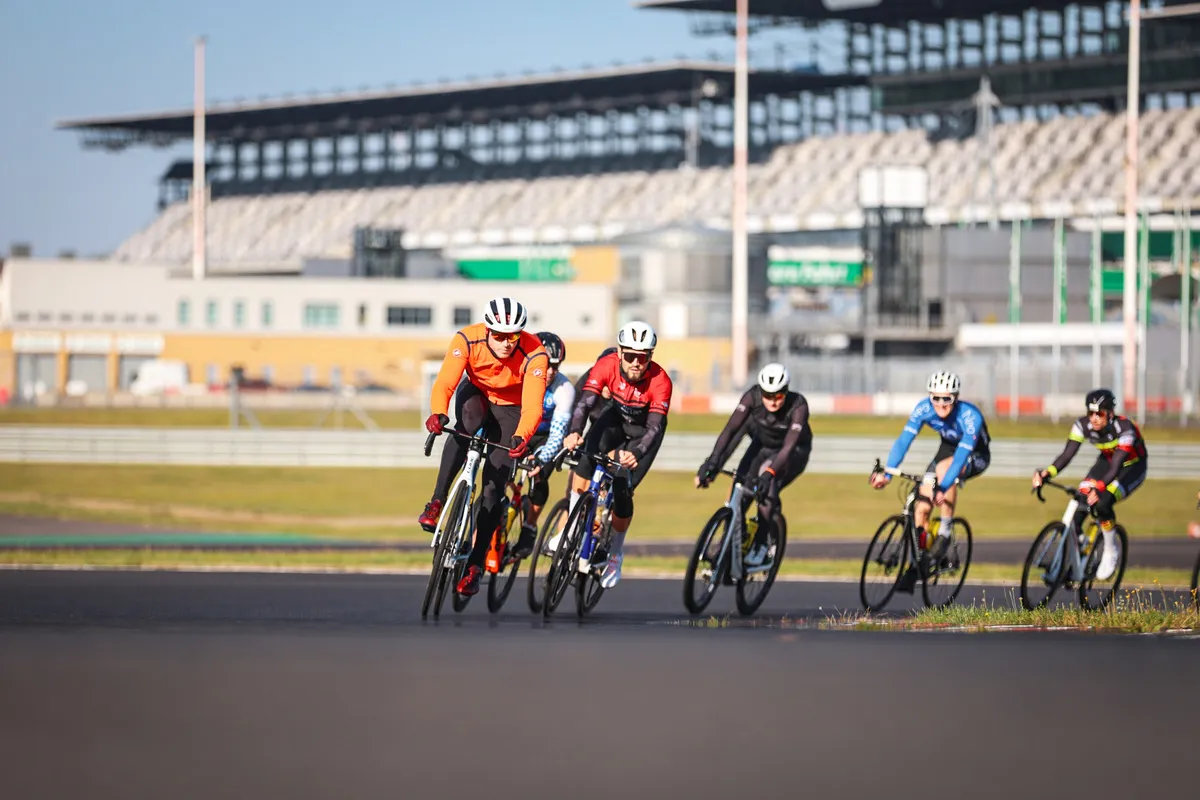 Gruppe von Rennradfahrern auf dem Lausitzring mit Tribüne im Hintergrund