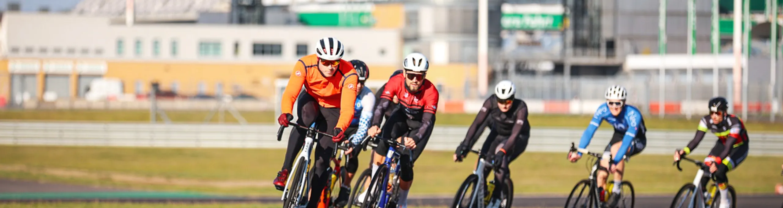 Gruppe von Rennradfahrern auf dem Lausitzring mit Tribüne im Hintergrund