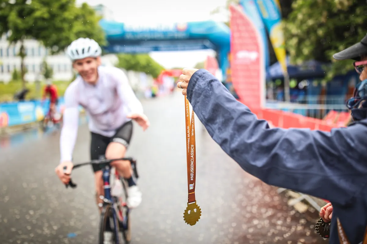 Rennradfahrer wird eine Finisher Medaille überreicht