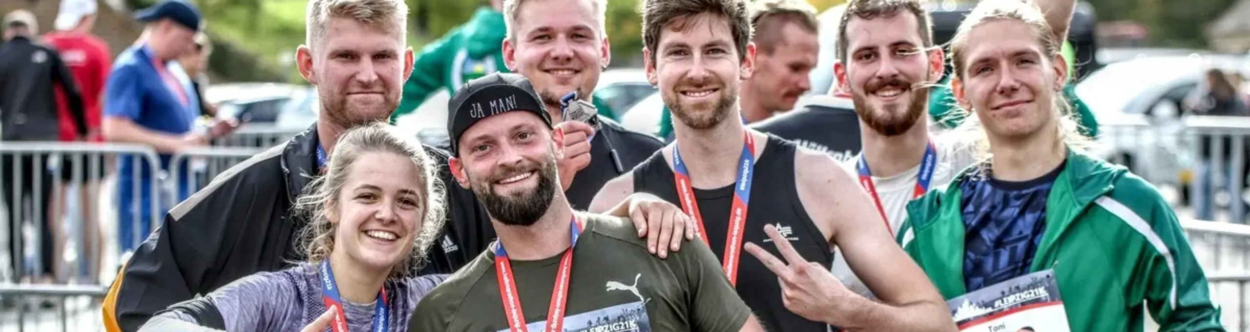 Lächelnde Gruppe von Läufern halten ihre Finisher-Medaillen in die Kamera