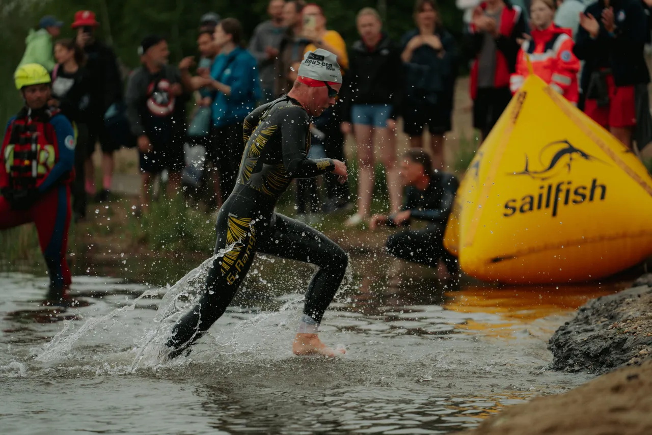 Läufer in Neoprenanzug kommt aus dem Gremmlitzer See